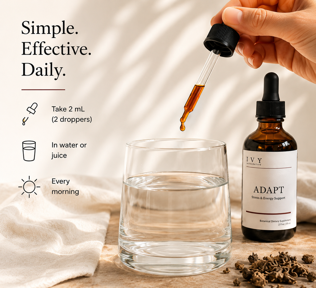 Hand using a dropper to add liquid from a bottle labeled 'Adapt' into a glass on a wooden surface.